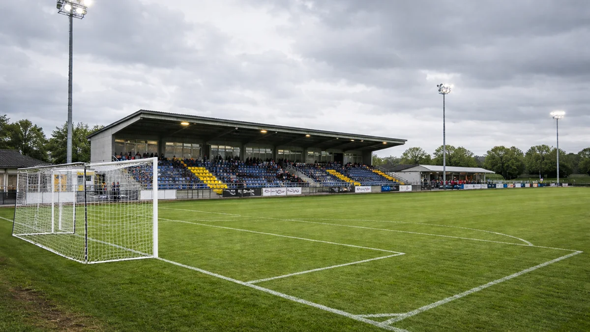 Stade de football amateur avec pelouse et tribunes modestes